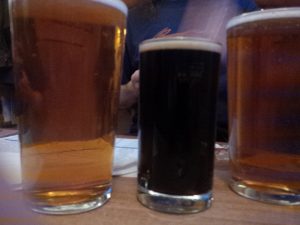 Two pints of Tiny Rebel FUBAR flanking a Saltaire Triple Chocolate Stout